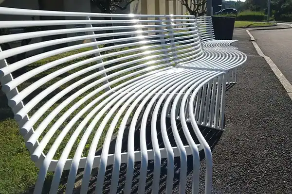 Zeroquindici.015 curved benches in white alongside a campus path at Binghamton University